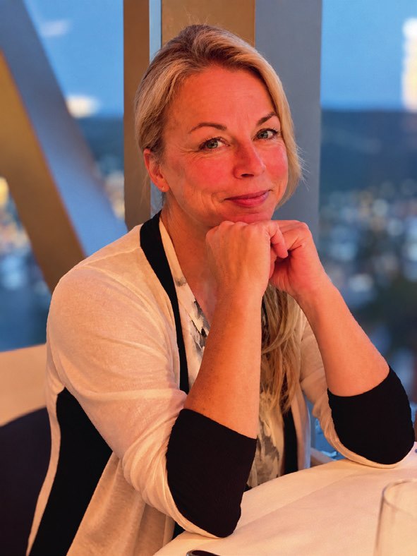 Sandra Gottschalk sitzt lächelnd an einem Tisch